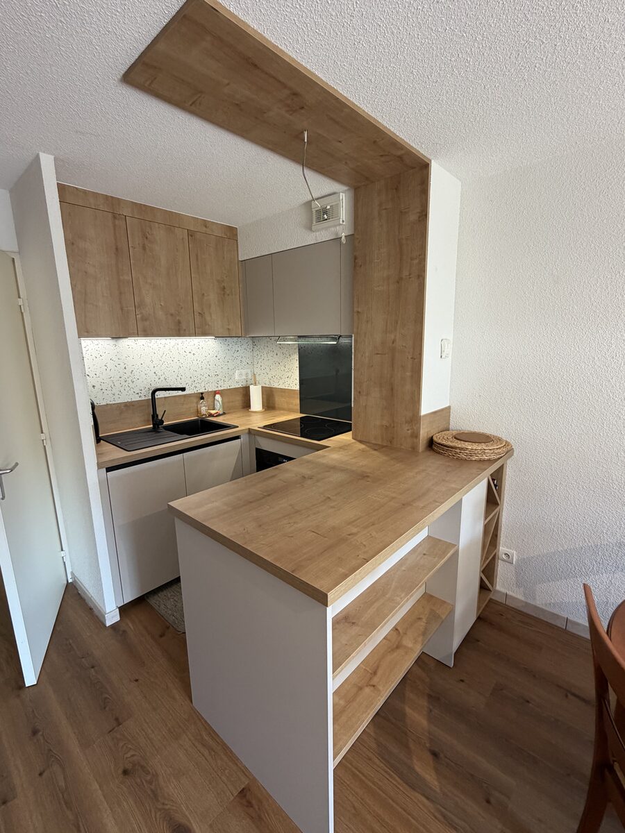 Cuisine compacte bois et blanc avec îlot bar et crédence terrazzo